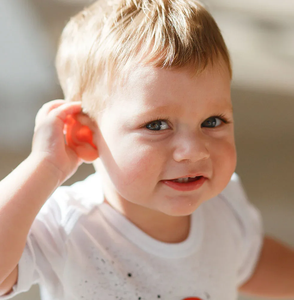 Toddler holding his hand to his ear and smiling | Earwell Surgery in Orlando