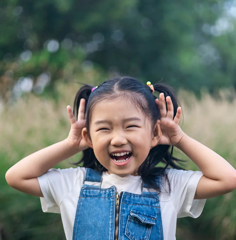 Young girl with ponytails showing her ears and smiling | Earwell Surgery in Orlando