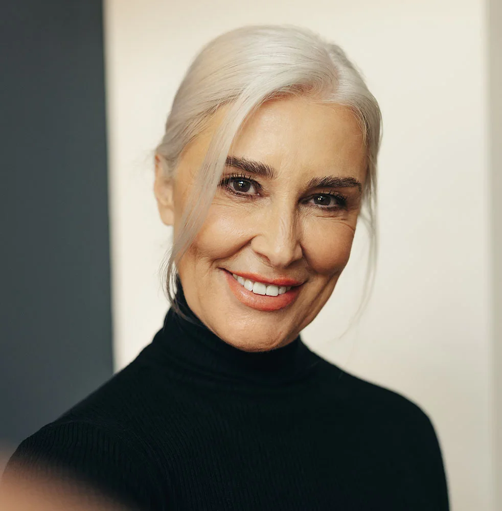 Older woman in a black turtleneck smiling | Eyelid Surgery in Orlando