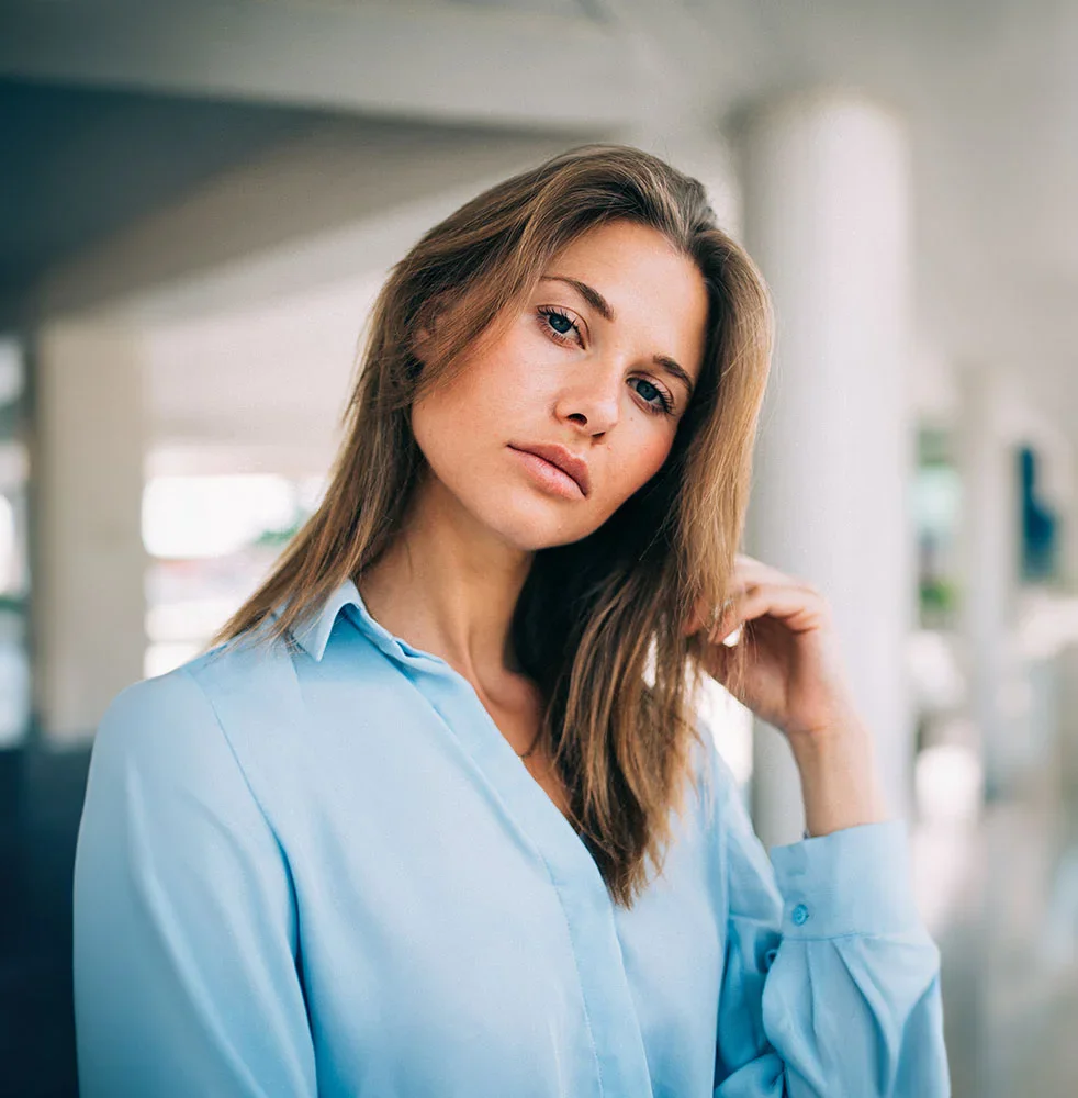 Dark blonde woman in a blue shirt looking ahead | Facelifts in Orlando